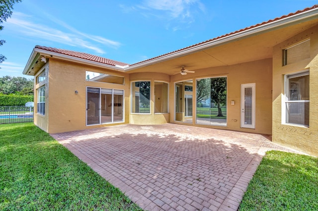 rear view of property with a patio, a lawn, and ceiling fan