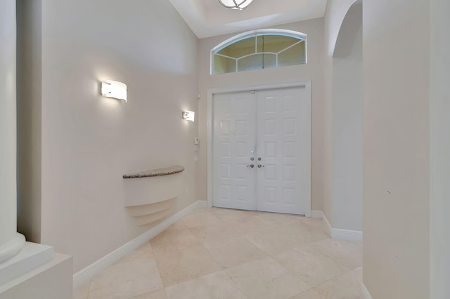 entrance foyer featuring high vaulted ceiling, decorative columns, and light tile patterned floors