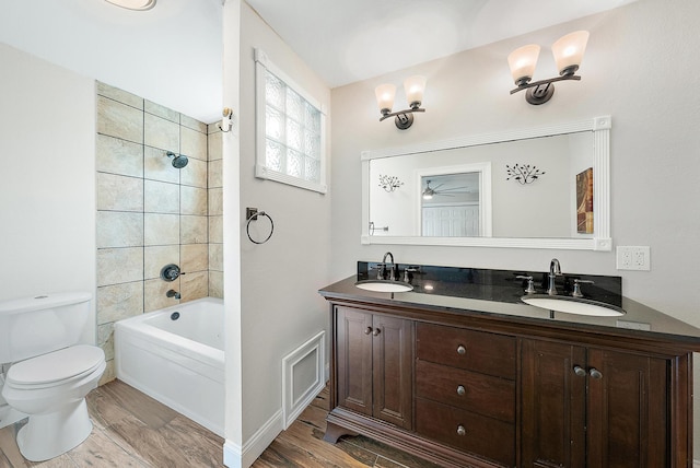 full bathroom with vanity, toilet, tiled shower / bath, and hardwood / wood-style floors