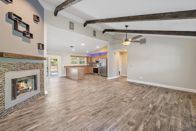 unfurnished living room with light hardwood / wood-style floors, vaulted ceiling with beams, and ceiling fan