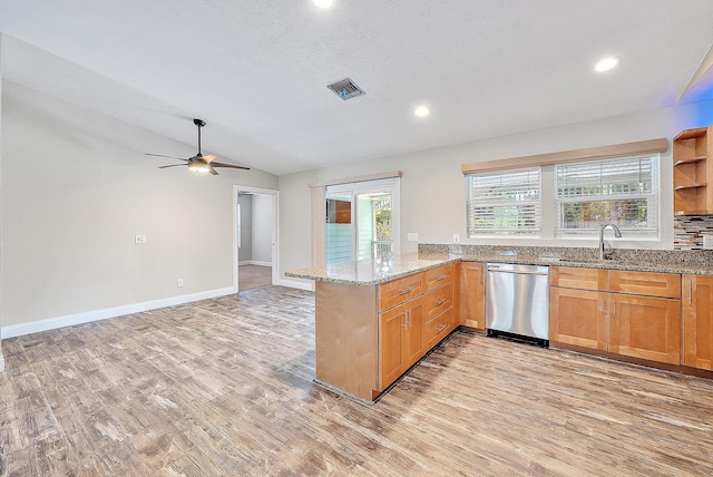 kitchen with dishwasher, kitchen peninsula, vaulted ceiling, light wood-type flooring, and light stone counters