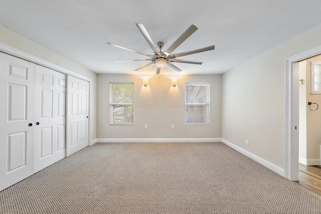 unfurnished bedroom with light carpet, a textured ceiling, a closet, and ceiling fan