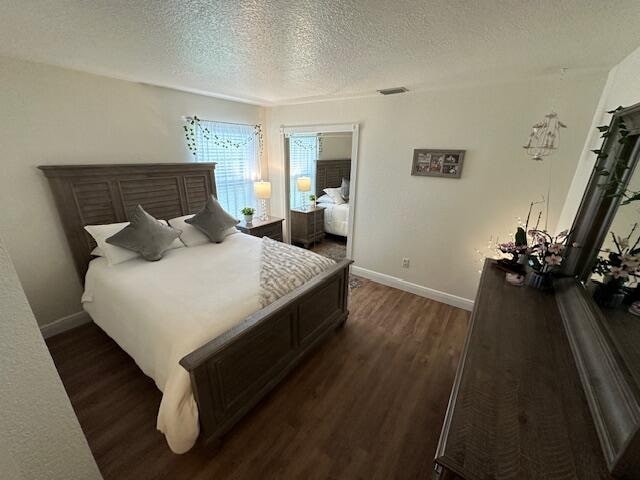 bedroom with a textured ceiling and dark hardwood / wood-style floors