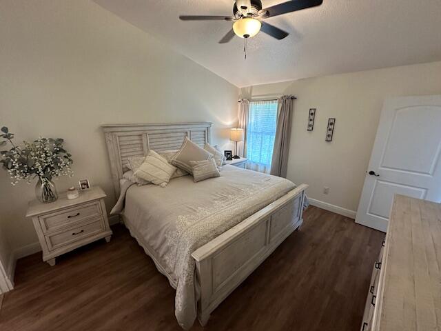 bedroom with ceiling fan, lofted ceiling, and dark hardwood / wood-style flooring