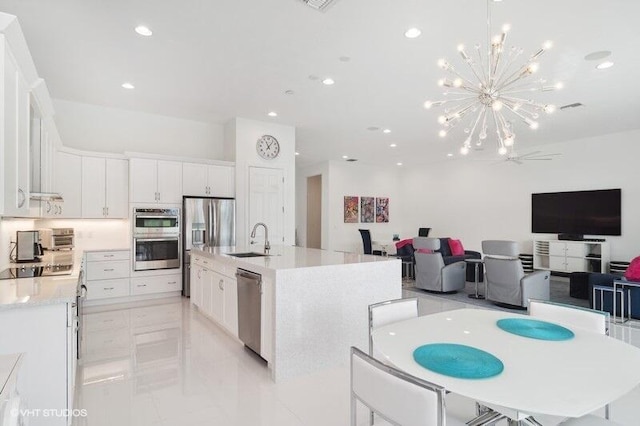 kitchen featuring sink, hanging light fixtures, appliances with stainless steel finishes, a kitchen island with sink, and white cabinets