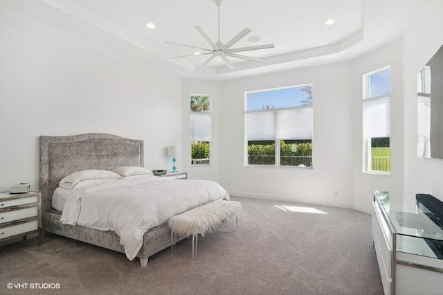 carpeted bedroom featuring ceiling fan and a tray ceiling