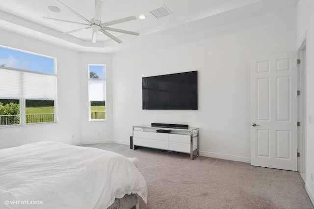 bedroom with ceiling fan, a raised ceiling, and light colored carpet