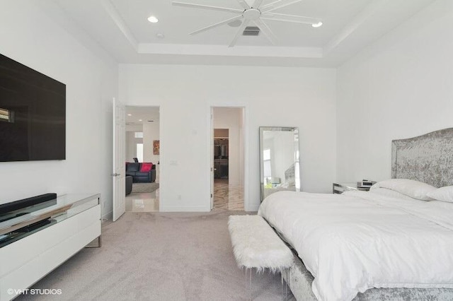 bedroom with a raised ceiling, light colored carpet, and ceiling fan