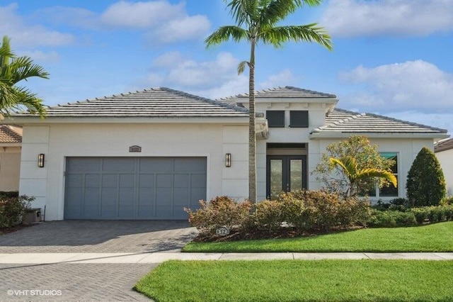 mediterranean / spanish house with a garage, a front yard, and french doors