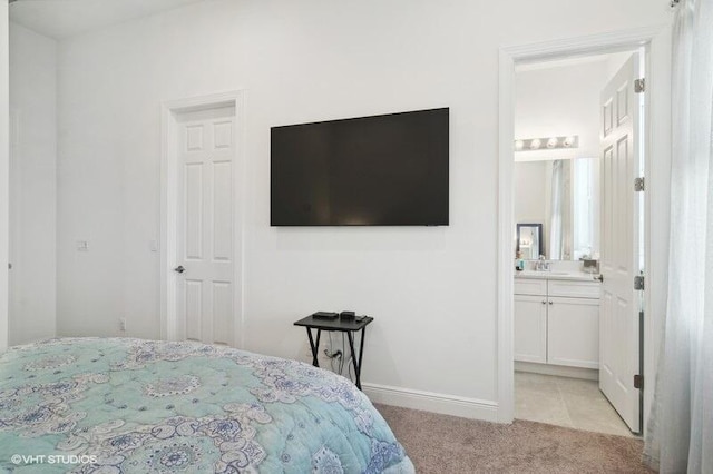 bedroom with light colored carpet and ensuite bath