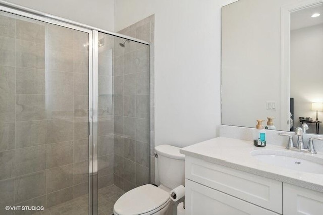 bathroom with a shower with door, vanity, and toilet