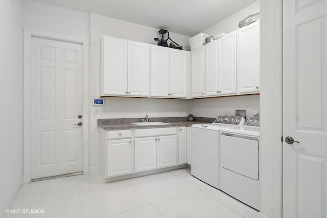 clothes washing area with sink, washer and clothes dryer, cabinets, and light tile patterned flooring