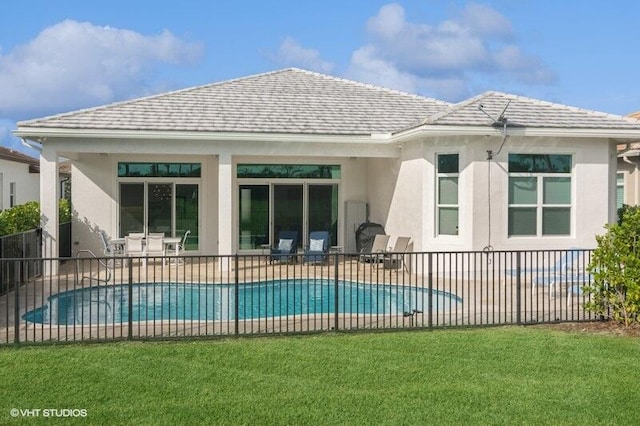 back of house with a fenced in pool, a lawn, and a patio