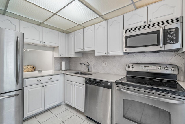 kitchen featuring stainless steel appliances, sink, light tile patterned floors, white cabinets, and tasteful backsplash