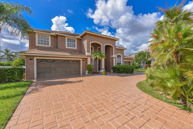 mediterranean / spanish-style home with a garage and a front lawn