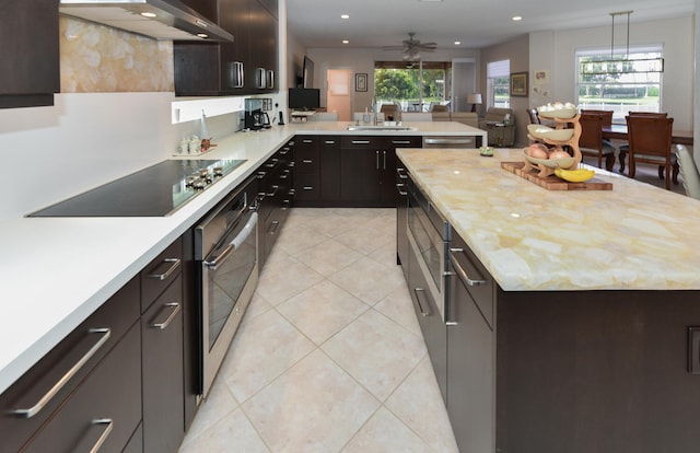 kitchen with wall chimney exhaust hood, kitchen peninsula, pendant lighting, black electric stovetop, and sink