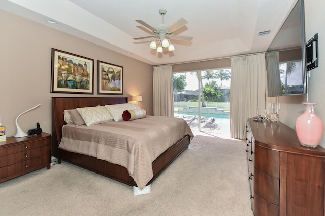 bedroom featuring ceiling fan, light carpet, a raised ceiling, and access to exterior