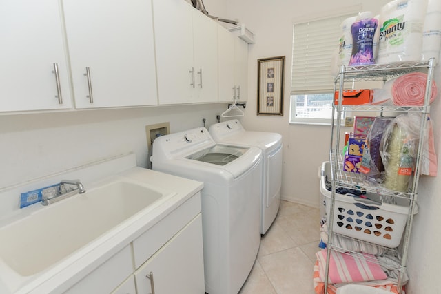 laundry room with sink, light tile patterned floors, washing machine and dryer, and cabinets