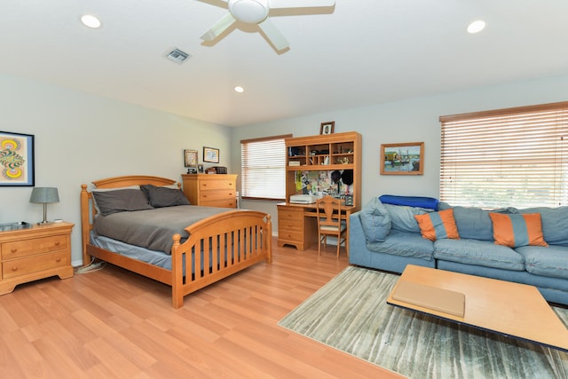 bedroom with ceiling fan, multiple windows, and light hardwood / wood-style flooring