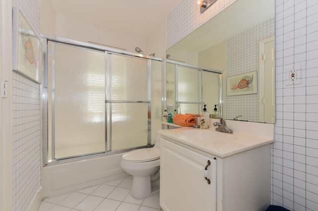 full bathroom featuring bath / shower combo with glass door, tile walls, toilet, vanity, and tile patterned floors