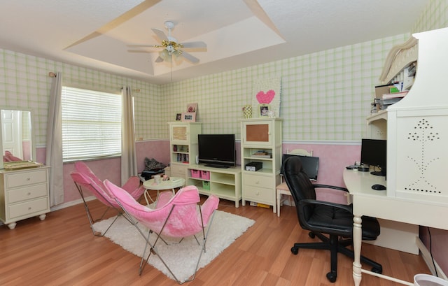 office space featuring ceiling fan, a raised ceiling, and light hardwood / wood-style flooring