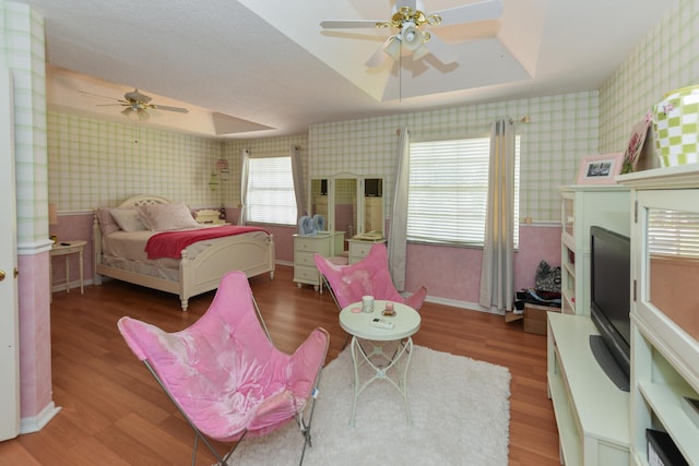 bedroom with hardwood / wood-style floors, a tray ceiling, and ceiling fan