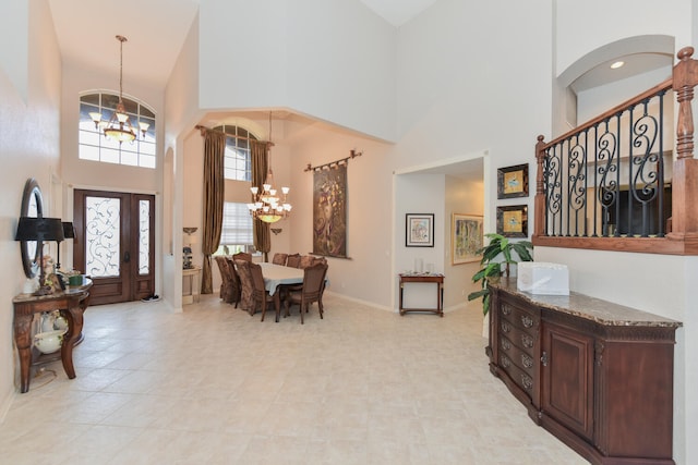 tiled entryway featuring an inviting chandelier and a high ceiling