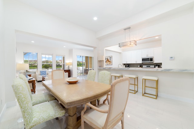 dining room featuring sink, a notable chandelier, and light tile patterned floors