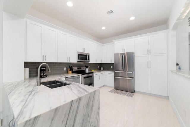 kitchen with light stone counters, stainless steel appliances, decorative backsplash, and white cabinets