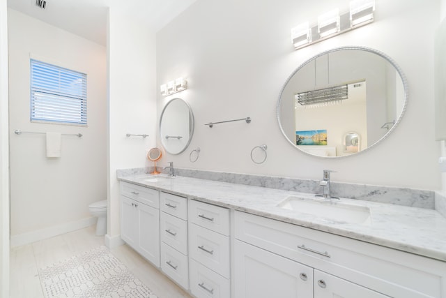 full bath featuring a sink, baseboards, toilet, and double vanity