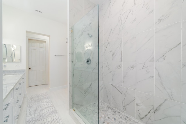 bathroom with a marble finish shower, baseboards, and vanity