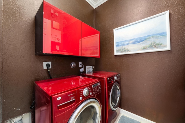 clothes washing area with washing machine and dryer, baseboards, and a textured wall