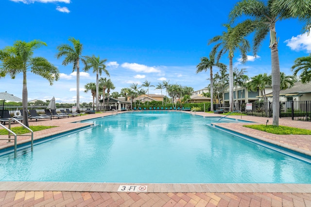 community pool with a patio area, fence, and a residential view