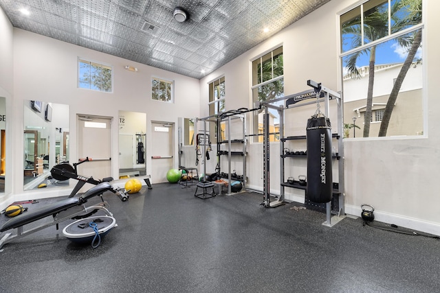 gym with plenty of natural light, visible vents, a high ceiling, and baseboards