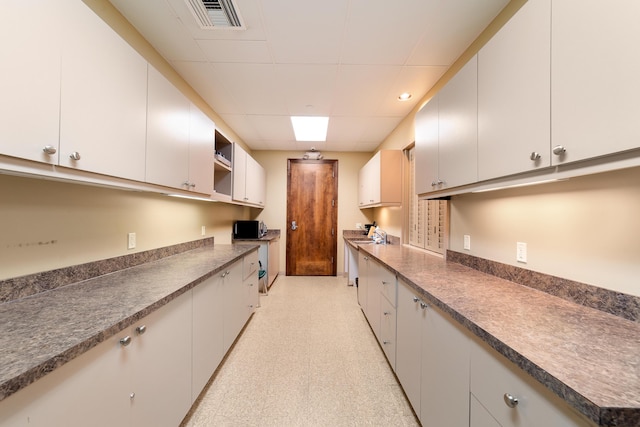 kitchen featuring dark countertops, visible vents, light floors, and a drop ceiling