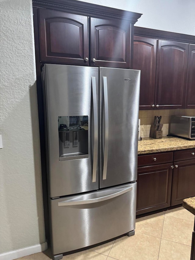 kitchen with decorative backsplash, stainless steel refrigerator with ice dispenser, light tile patterned floors, and light stone countertops