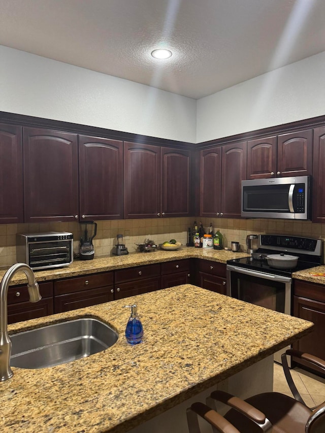 kitchen featuring tasteful backsplash, light stone countertops, sink, and appliances with stainless steel finishes