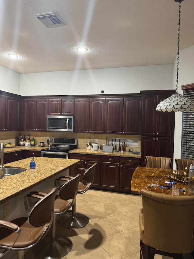 kitchen featuring tasteful backsplash, sink, decorative light fixtures, and appliances with stainless steel finishes