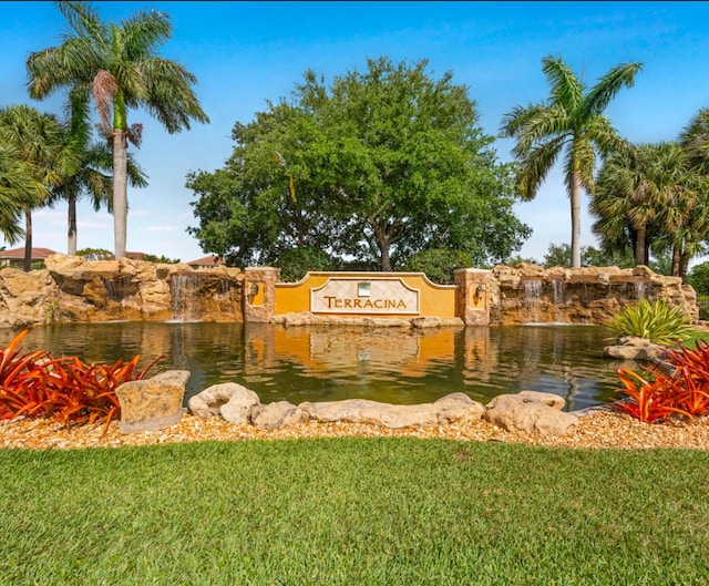 community sign featuring a lawn and a water view