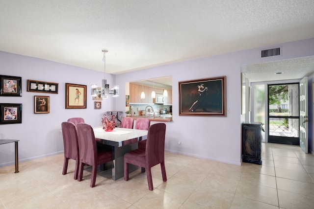 dining area featuring sink, a notable chandelier, a textured ceiling, and light tile patterned floors