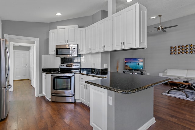 kitchen featuring appliances with stainless steel finishes, dark hardwood / wood-style flooring, kitchen peninsula, ceiling fan, and white cabinets