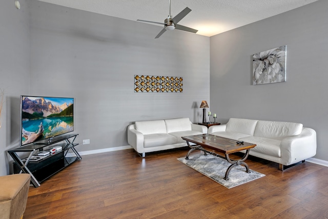 living room with dark wood-type flooring, ceiling fan, and a textured ceiling