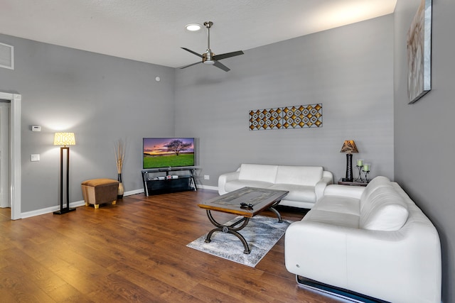 living room with a textured ceiling, ceiling fan, and dark hardwood / wood-style flooring