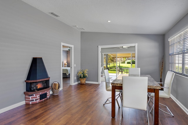 dining room with a wood stove, dark hardwood / wood-style floors, a healthy amount of sunlight, and ceiling fan