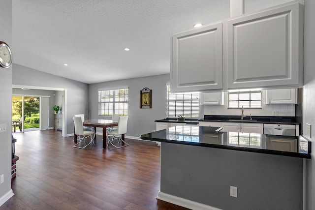 kitchen featuring lofted ceiling, kitchen peninsula, sink, white cabinetry, and dark hardwood / wood-style flooring