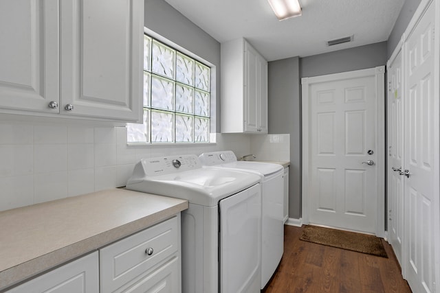 washroom featuring dark hardwood / wood-style flooring, a textured ceiling, washing machine and clothes dryer, and cabinets