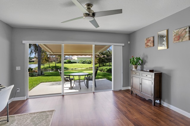 doorway with a textured ceiling, ceiling fan, and dark hardwood / wood-style flooring