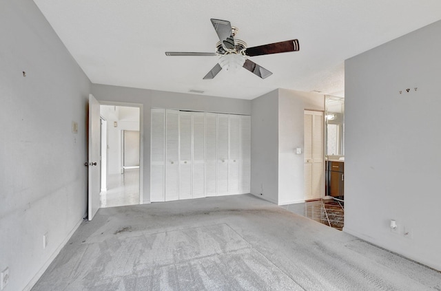 unfurnished bedroom featuring ceiling fan, ensuite bath, and carpet floors