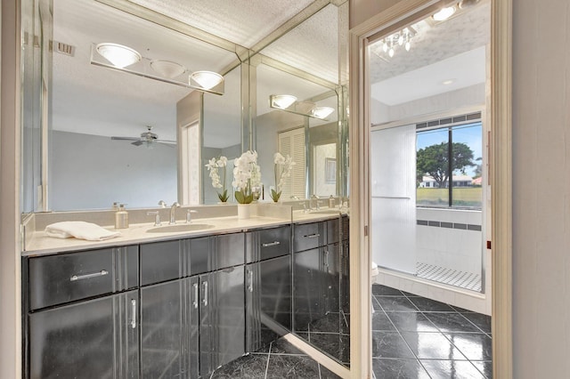 bathroom featuring ceiling fan, vanity, a tile shower, and tile patterned flooring