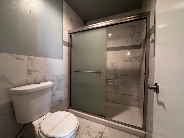 bathroom featuring tile walls, toilet, and an enclosed shower